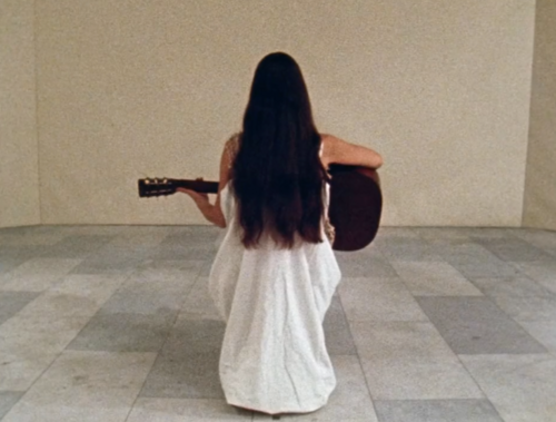 still of Meredith Monk holding a guitar from the film 16 Millimeter Earrings