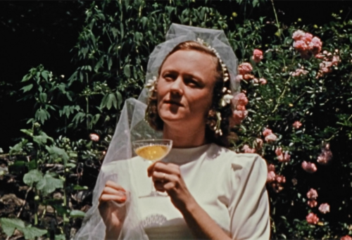 Cynthia Childs in a wedding dress holding a glass of champagne in the film Seductio Ad Absurdum