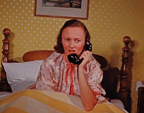 color photo of filmmaker Cynthia Childs on a bed, talking on the phone