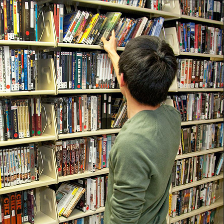 Patron with back to camera examines shelves of videos
