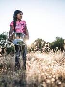 color image of young Apache chef holding a silver bowl in a field from the film Gather