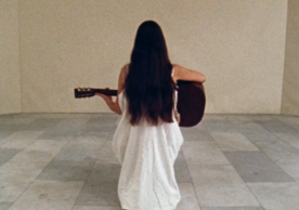 still of Meredith Monk holding a guitar from the film 16 Millimeter Earrings