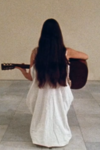still of Meredith Monk holding a guitar from the film 16 Millimeter Earrings