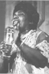 Black and white photo of Bessie Jones holding a microphone and singing