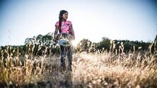 color image of young Apache chef holding a silver bowl in a field from the film Gather