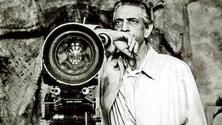 black and white photo of Satyajit Ray standing next to a movie camera